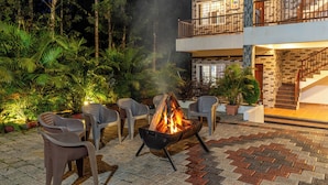 An outdoor patio with a fire pit, seating, and a staircase leading to a balcony. - Treebo Arabica Valley-Coffee Plantation Retreat (Chikkamagaluru)