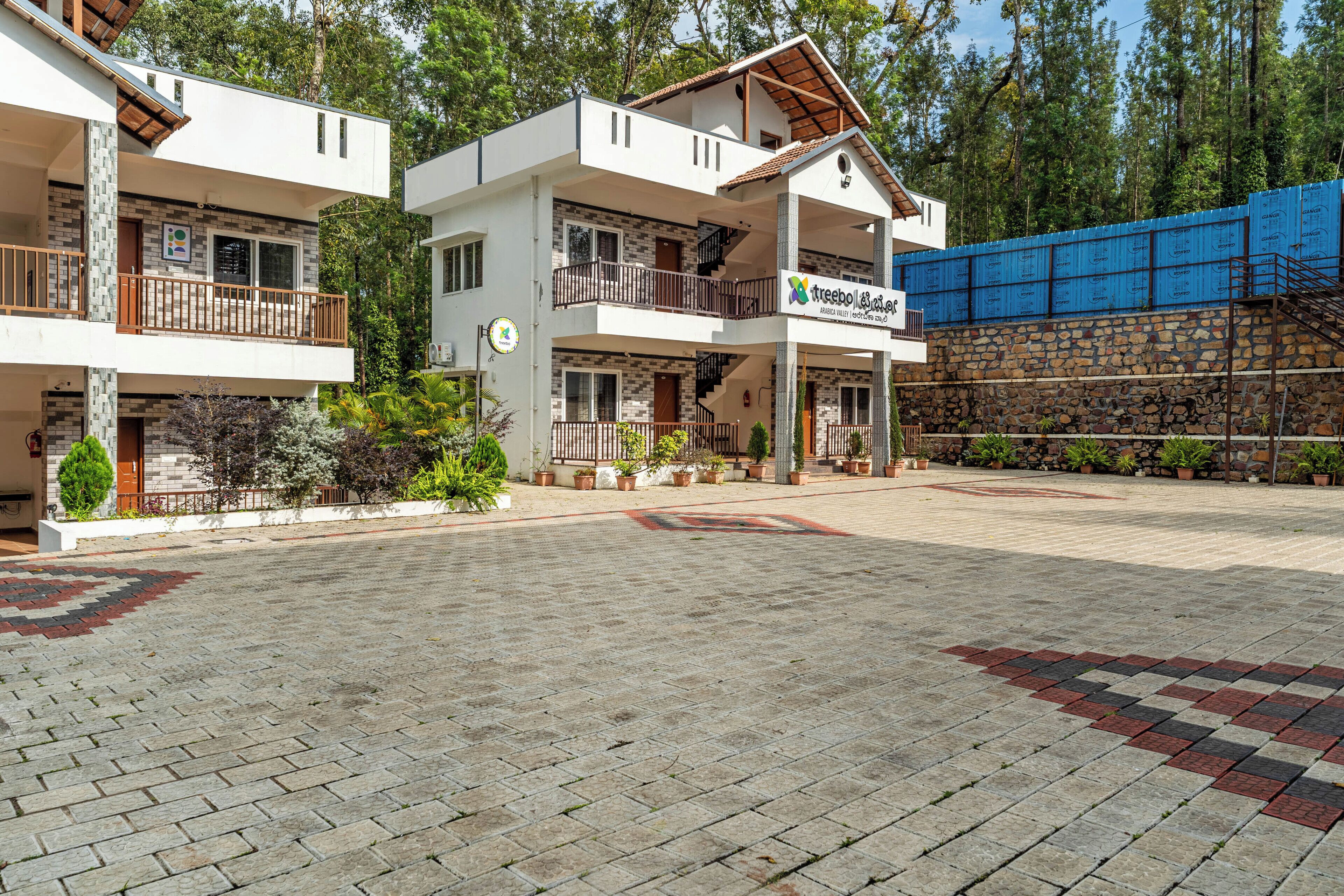 A two-story building with a balcony, a sign indicating a restaurant, and a stone wall in the background.