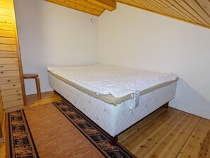 A single bed in a room with wooden flooring and a simple, unadorned wall. - Leipolevi 1 by Interhome (Kittilä)