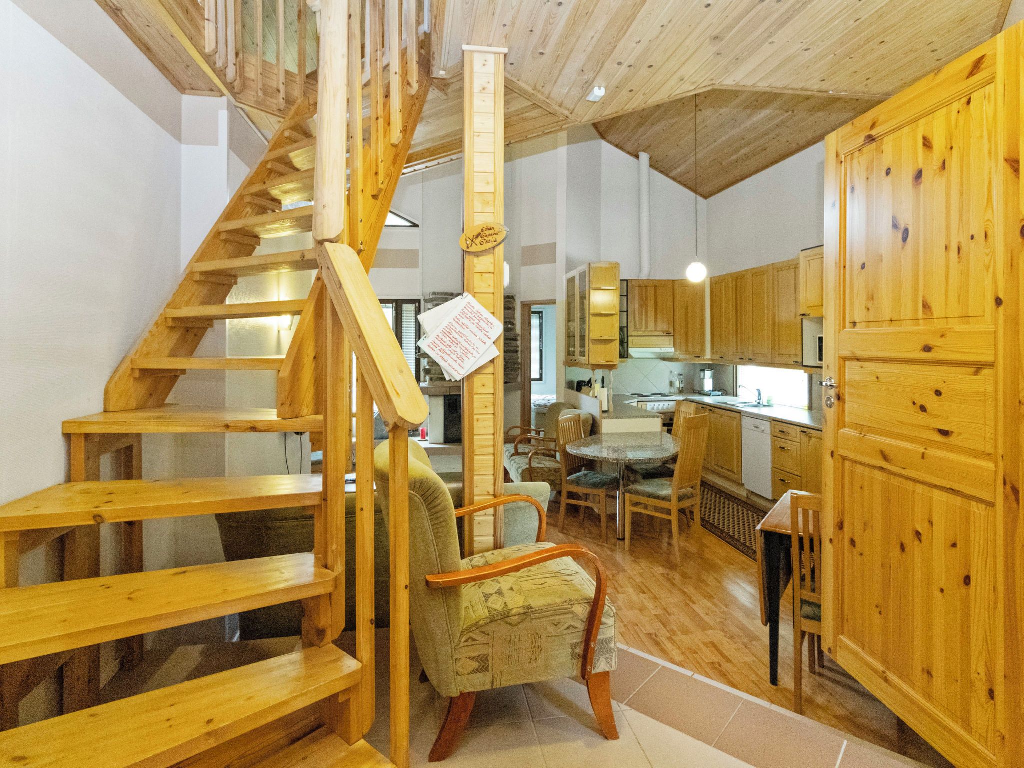Un interior de madera con una escalera espiral, una zona de comedor y una cocina.