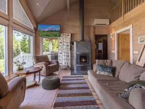 A cozy living room with a fireplace, wooden walls, and a sofa.