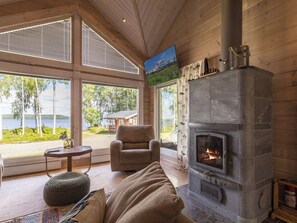 Une pièce chaleureuse avec une cheminée, un canapé confortable et une vue sur l’extérieur.