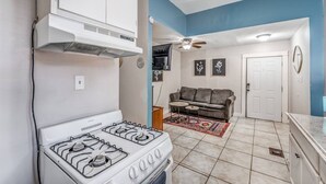 A compact kitchen with a stove, a ceiling fan, and a living area with a couch and a rug. - Cozy Central Hideaway in Midtown Memphis (Memphis)