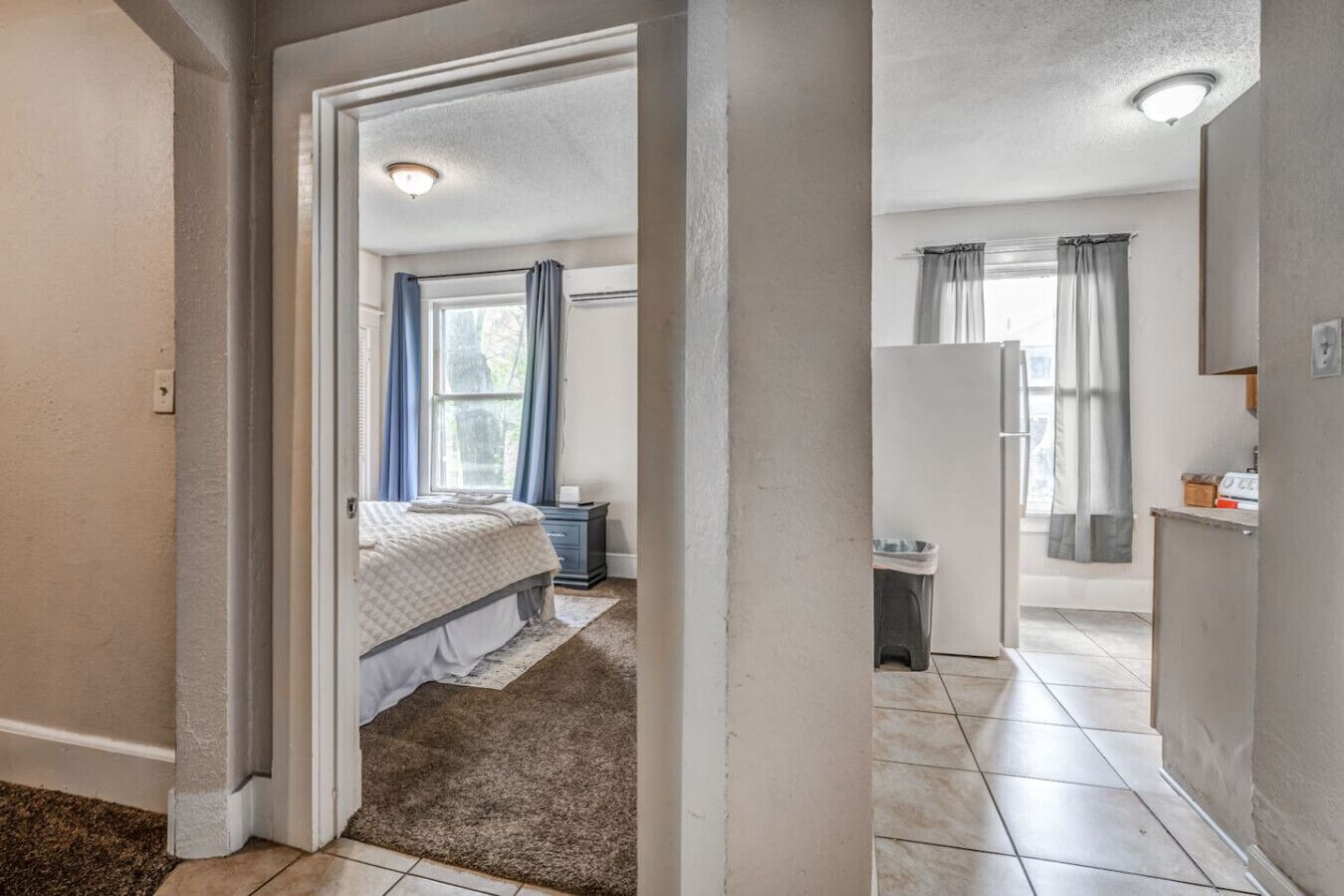 A bedroom with a bed, a nightstand, and a window with curtains.