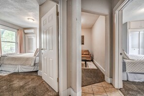 Une chambre à coucher avec un lit, une fenêtre et une porte donnant sur une autre pièce.