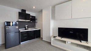 A modern kitchen with a built-in microwave, kettle, and a flat-screen TV on a white stand. - Urban loft 1BR T1-706 (Chalong)