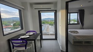 A modern hotel room with a balcony, a dining area with a table and chairs, and a bed. - Urban loft 1BR T1-706 (Chalong)