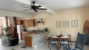 Una cocina moderna con armarios de madera, una isla integrada y un comedor con mesa y sillas.