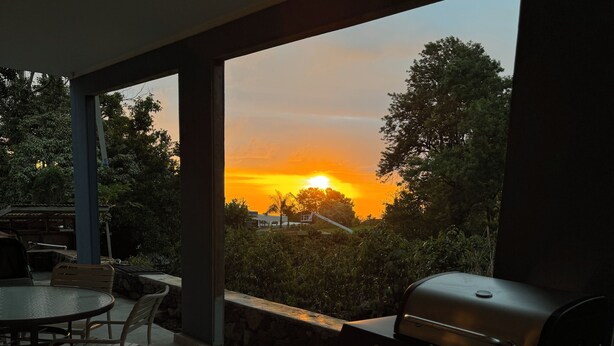 Un patio exterior con una parrilla y zona de comedor, con vistas a un atardecer.