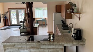 Una cocina moderna con una isla central, una zona de comedor con mesa de madera y vistas al salón.