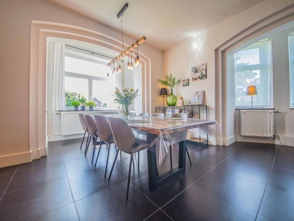 A modern kitchen with a dining table, chairs, and a pendant light.
