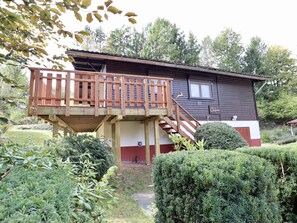 A two-story house with a wooden deck and a small window.