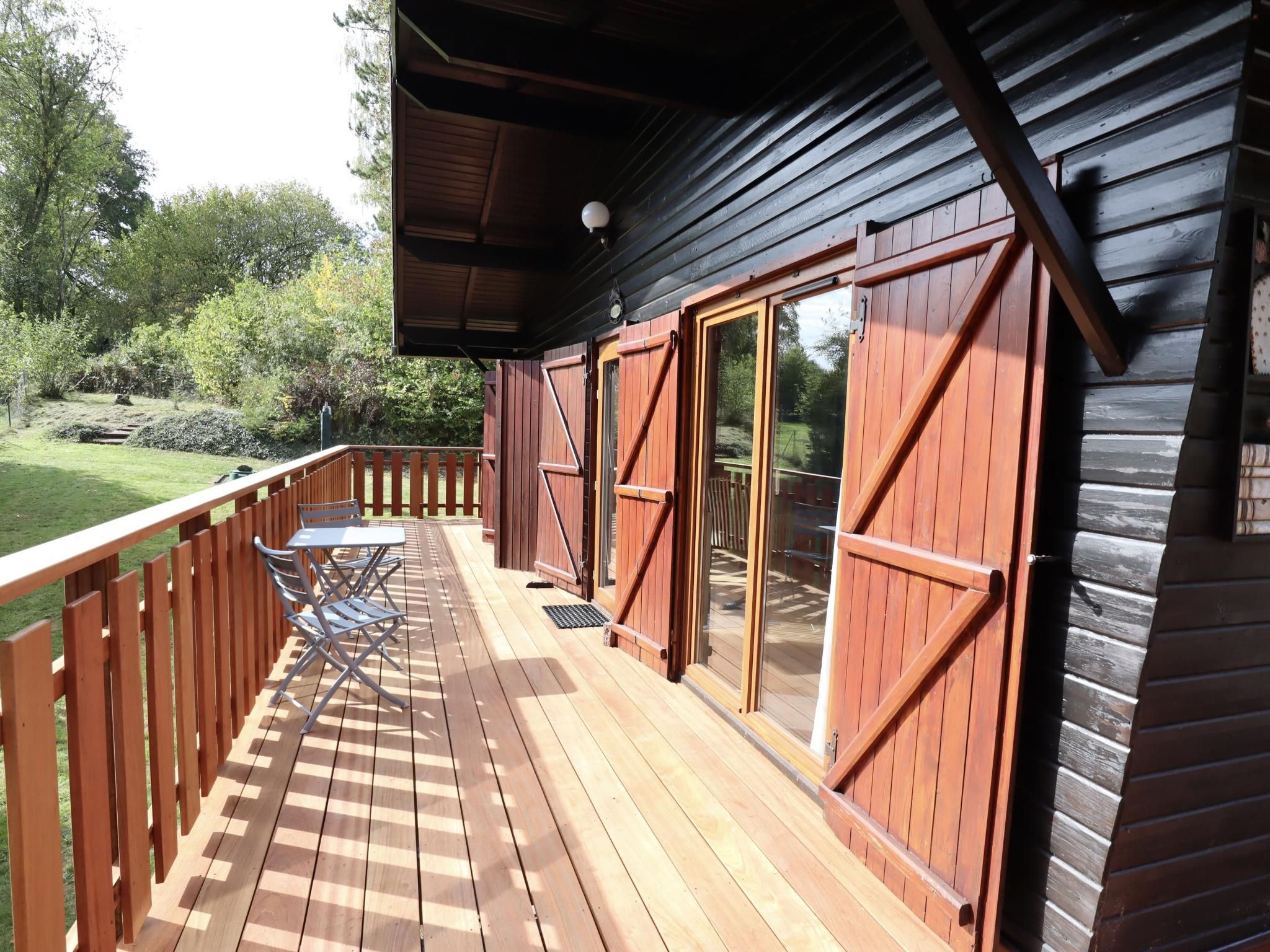 A wooden deck with a table and chairs, a sliding glass door, and a view of the surrounding greenery.