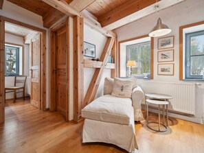 Une pièce chaleureuse avec un plafond en bois, un lit avec un oreiller, une petite table et une fenêtre ornée de tableaux.