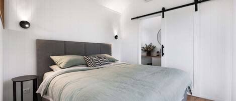 A bedroom with a bed, bedside table, wall-mounted light, and a sliding door closet.