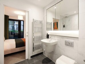 Een moderne badkamer met een grote spiegel, een witte wastafel en een handdoekrek.