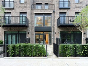 Een modern, meerlaags gebouw met balkons, grote ramen en een hekwerk.