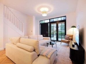 A living room with a sofa, a coffee table, a TV, and a staircase.
