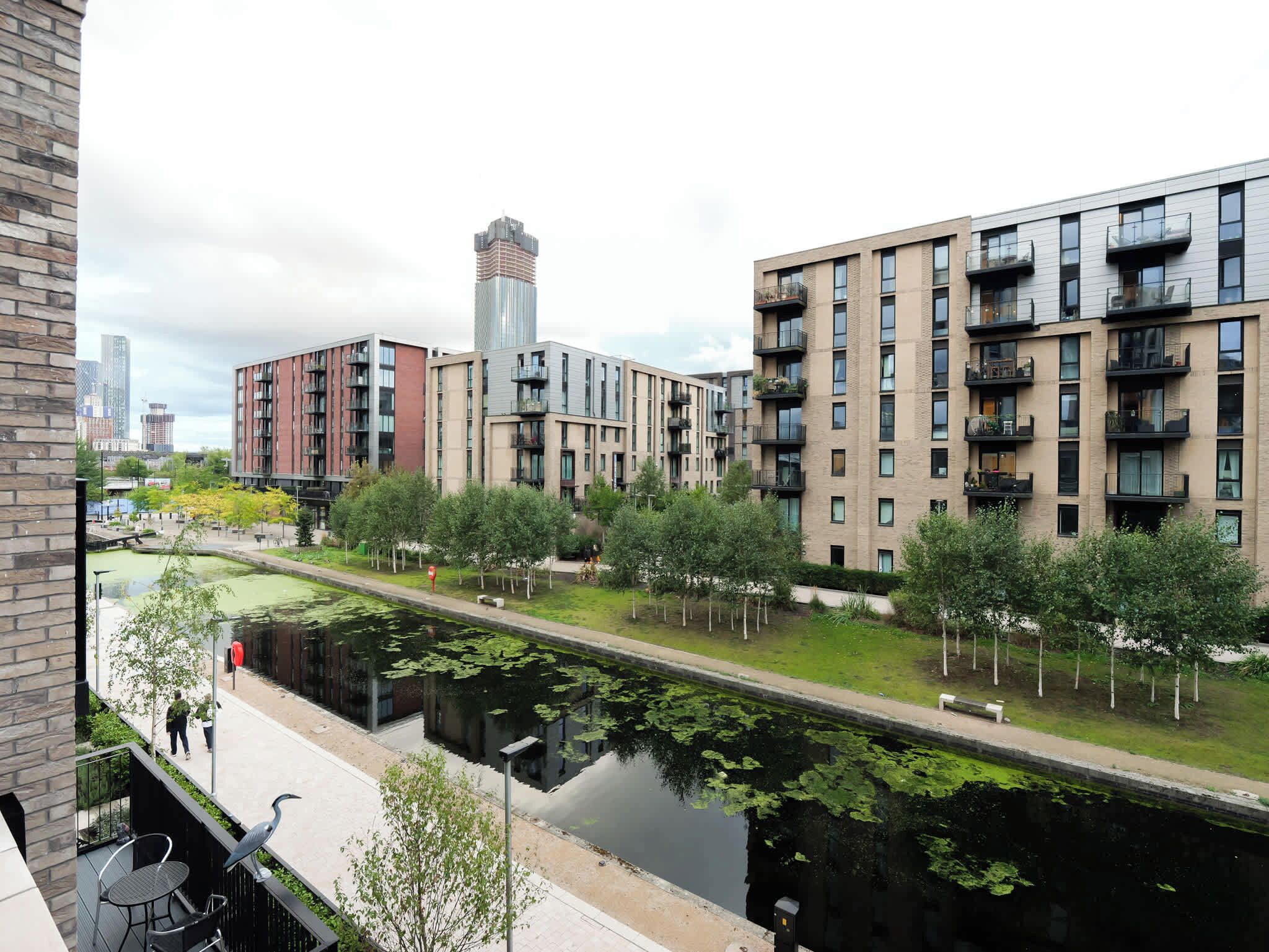 Una zona residencial moderna en la ciudad, con edificios de varios pisos, un canal y un paseo peatonal.