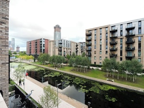 A modern urban residential area with multi-story buildings, a canal, and a pedestrian walkway.
