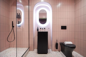 Et moderne badeværelse med bruser, toilet og vask med spejl.