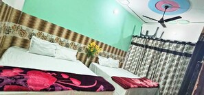 Ein Hotelzimmer mit zwei Betten, einem Deckenventilator und einem blumigen Vorhang.