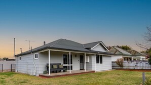 A single-story house with a porch, a small deck, and a fenced backyard.