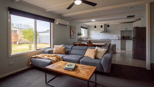 A modern living room with a grey sofa, a wooden coffee table, and a ceiling fan.