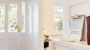 A white door with a framed welcome sign and a clipboard on a white table. - Hilltop Victorian Retreat - Firepit + Sunset views (Castlemaine)