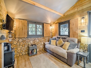 Ein gemütliches Blockhaus-Interieur mit Kamin, einer Couch, einem Fernseher und einem Bücherregal.