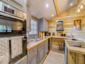Una cocina moderna con electrodomésticos de acero inoxidable, armarios de madera y techo de madera.
