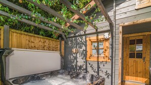 Un jacuzzi en un área exterior de madera con un cerco de madera y una ventana.