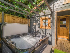 A hot tub in a wooden outdoor area with a wooden fence and a window.