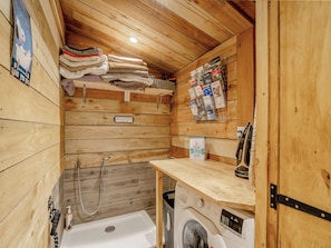 Interior de madera con lavadora, perchero y un mueble para revistas.