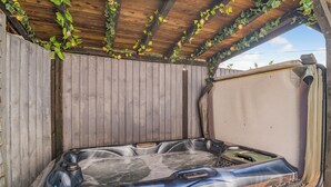 Un jacuzzi con cubierta de madera y una pérgola encima.