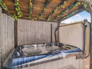 Un jacuzzi con cubierta de madera y una pérgola encima.