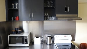 Une cuisine compacte équipée d’un four à micro-ondes, d’un grille-pain, d’une bouilloire et d’une plaque de cuisson.