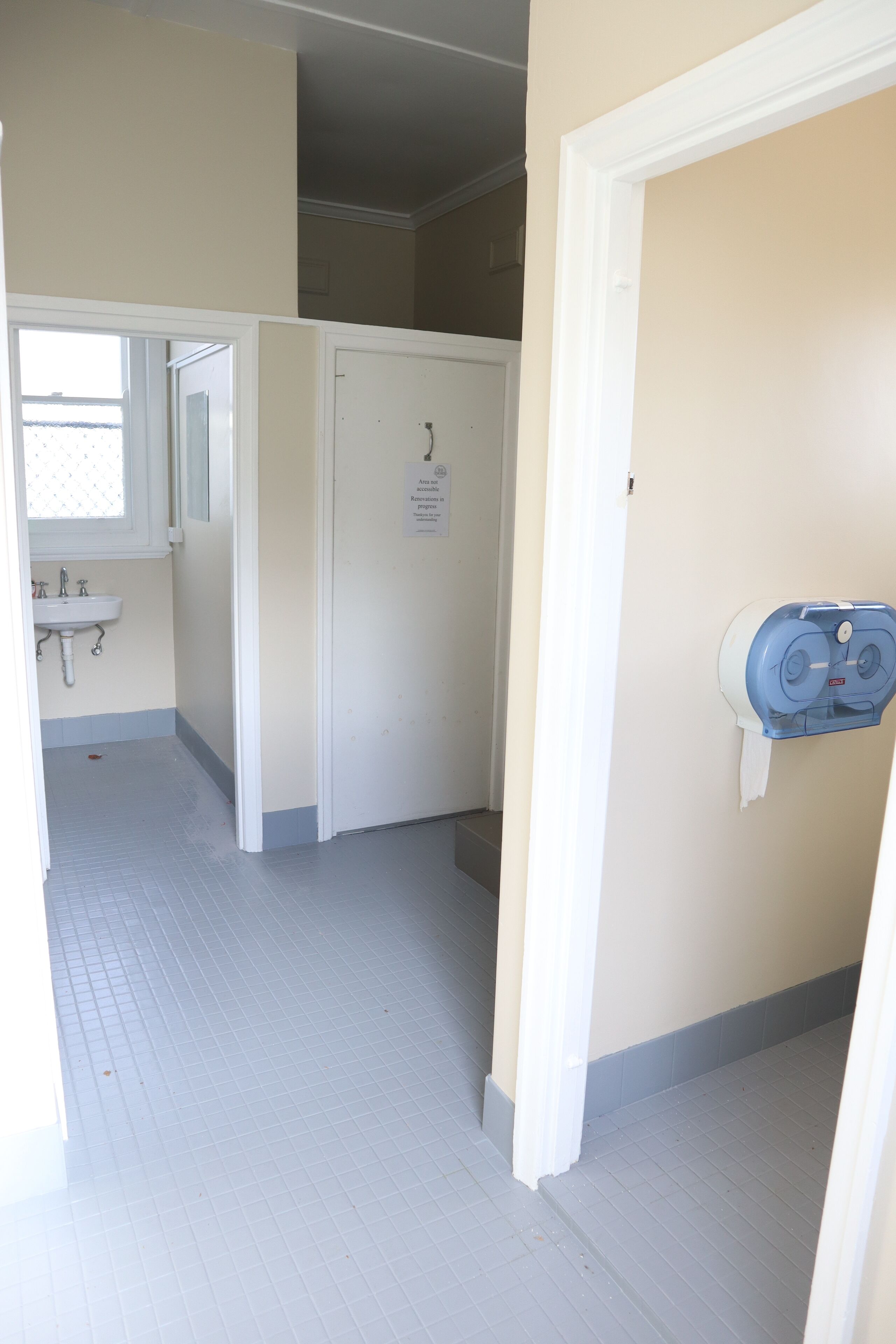 A bathroom with a sink, a toilet, and a paper towel dispenser.
