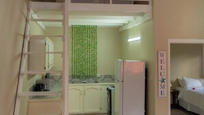 Habitación compacta con literas, un pequeño kitchenette, una mesa de comedor y una escalera para la litera superior.