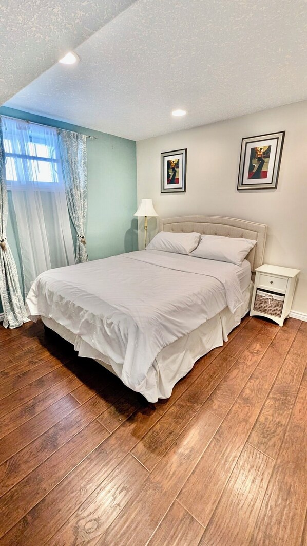 Une chambre à coucher avec un lit, une table de chevet, une lampe et deux tableaux encadrés accrochés au mur.