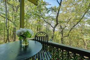 A table with a vase of flowers on a balcony with a view of a forest. - Hike, Fish & Golf: Condo 5 Mi to Ozone Falls! (Crab Orchard)