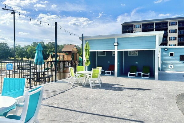 Un espacio al aire libre con patio, mesa de billar, sillones de descanso y una estructura de juegos.