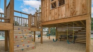 A wooden play structure with climbing holds and swings. - Table Rock Lake Retreat: Steps to Water & Pools! (Kimberling City)
