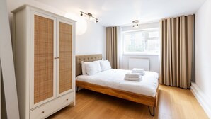 Een slaapkamer met een bed, een kledingkast, een raam met gordijnen en een radiator.