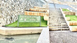 A convention center lobby with a stone wall, a green sign indicating directions, and a set of stairs leading to an upper level. - Family/Friends Hotel in Terrific Honolulu  Room, AC (Honolulu)