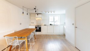 Een moderne keuken met witte kastjes, een houten eettafel en een inbouwoven.