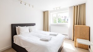 Een hotelkamer met een groot bed, een houten nachtkastje en een raam met gordijnen.