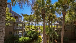 A residential area with multiple houses, palm trees, and a clear blue sky. - Ocean Views, Serene Back Deck, Easy Walk to Beach. Beautiful Seaside, Dog-Friendly Villa Awaits You! (Kiawah Island)