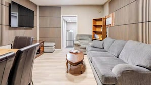 Un salon moderne avec un mur recouvert de panneaux en bois, un canapé gris, une table basse en bois et un téléviseur fixé au mur.