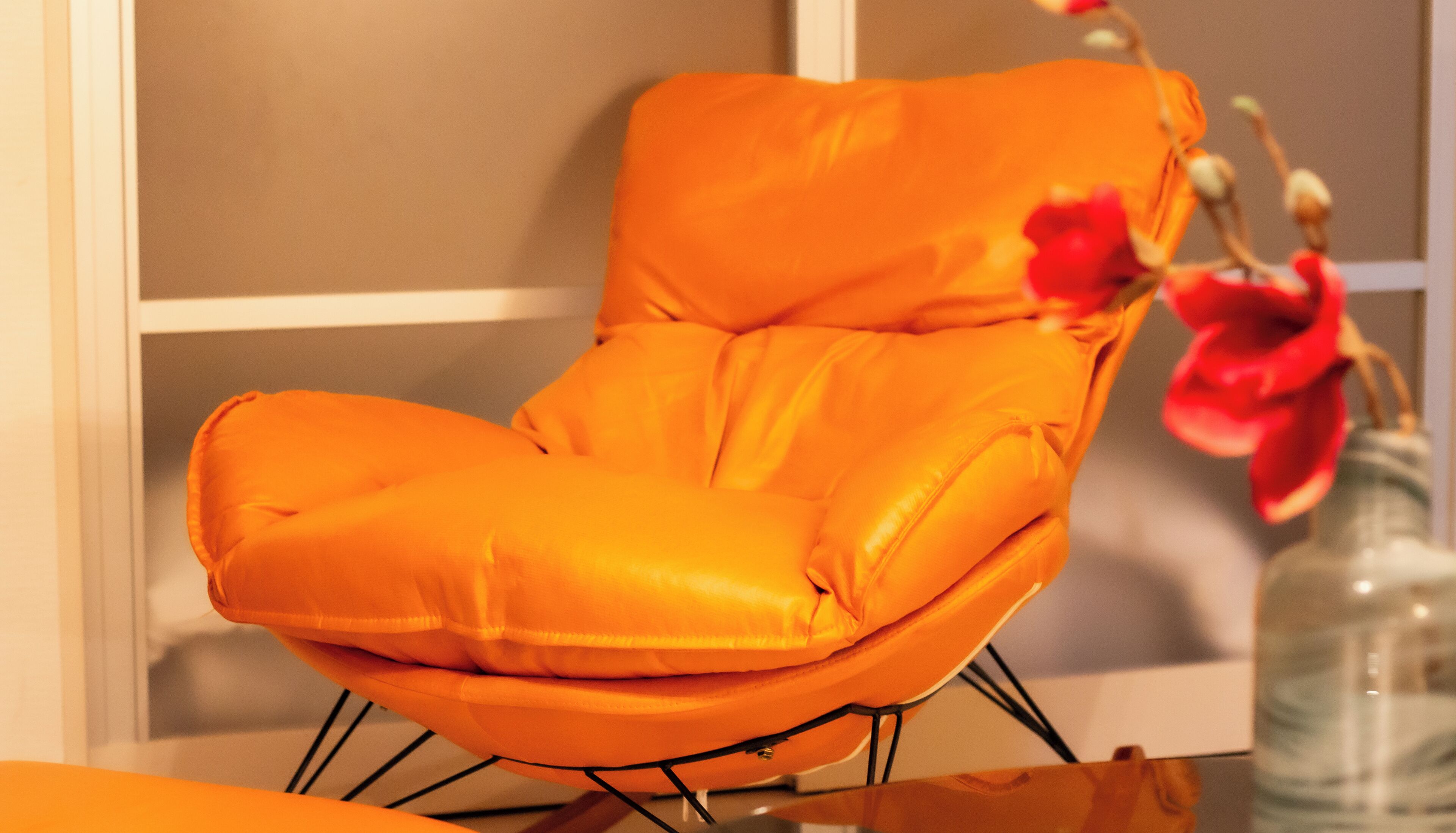 Una silla moderna color naranja con estructura metálica, colocada sobre una mesa de madera.
